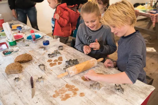 Children using cookie cutters to shape gingerbread dough at a messy baking table